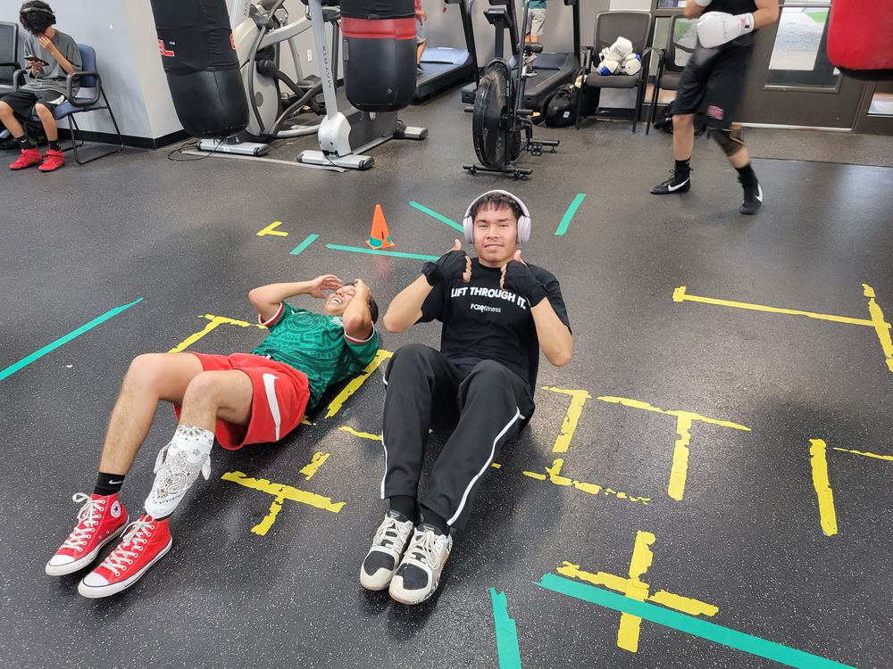 Two athletes doing core conditioning work on the gym floor